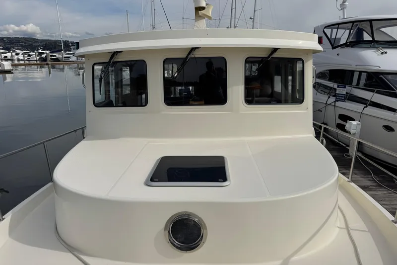 Slide: The Image of 2004 Nordic Tug 42 docked at marina, showcasing front cabin and windows. - 44