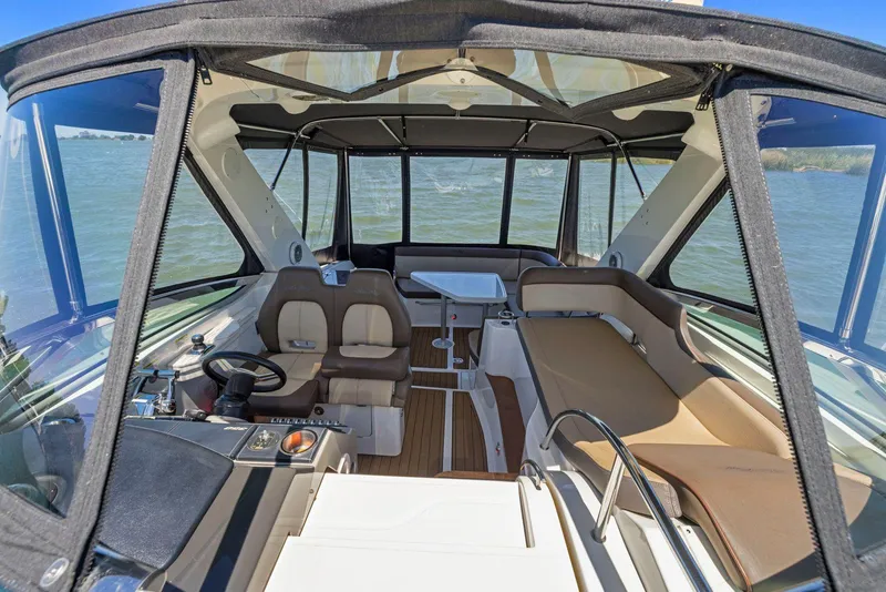 Slide: The Image of 2014 Sea Ray 350 Sundancer interior with seating and helm, overlooking water. - 10