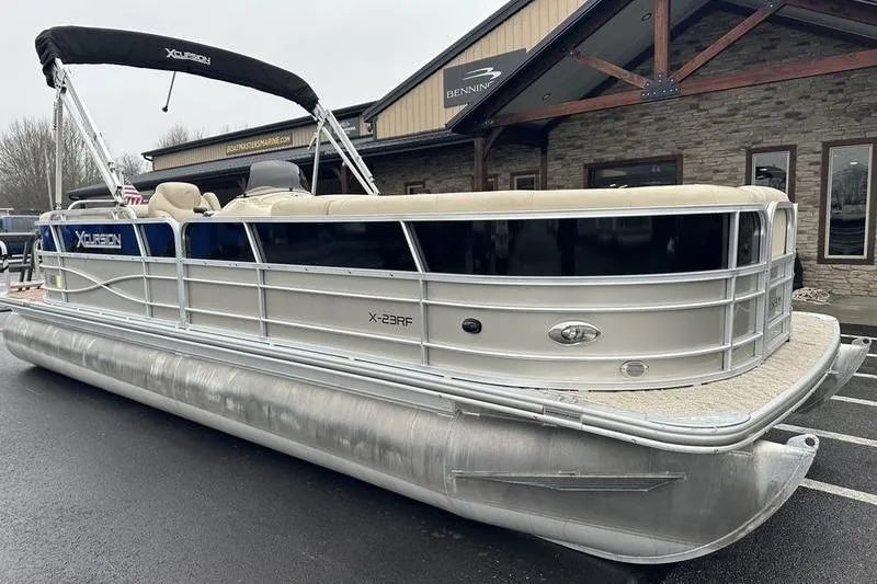 Slide: The Image of 2012 Xcursion X23RF pontoon boat parked outside a building on a rainy day. - 0