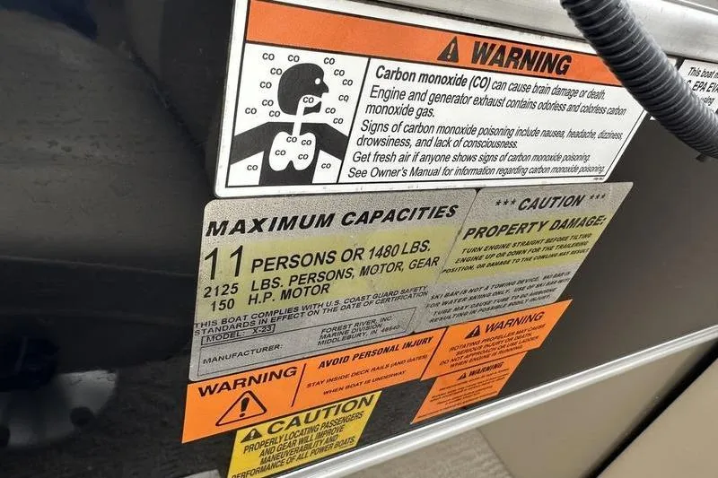 Slide: The Image of Warning labels on 2012 Xcursion X23RF boat, detailing carbon monoxide risks and capacity limits. - 12