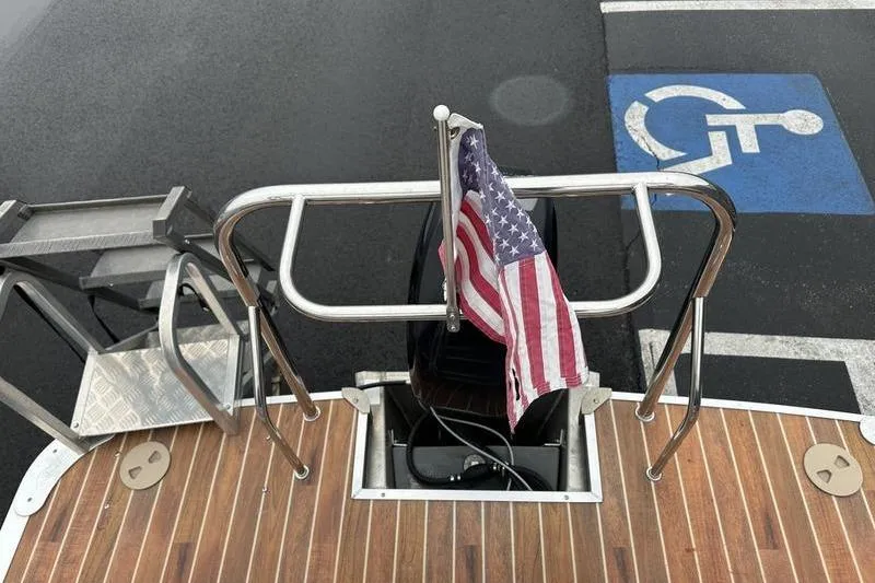 Slide: The Image of 2012 Xcursion X23RF boat with American flag, docked near accessible parking space. - 24