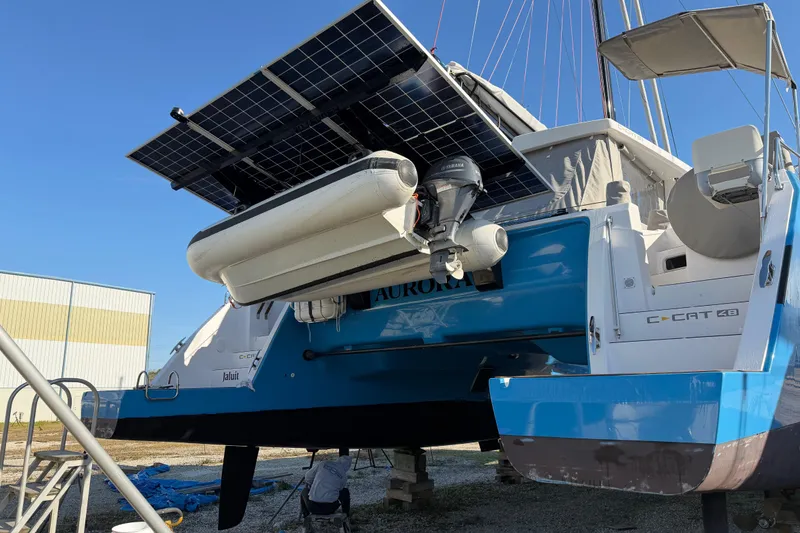 Slide: The Image of 2025 C-Catamarans 48 with solar panels and dinghy, docked under clear blue sky. - 12