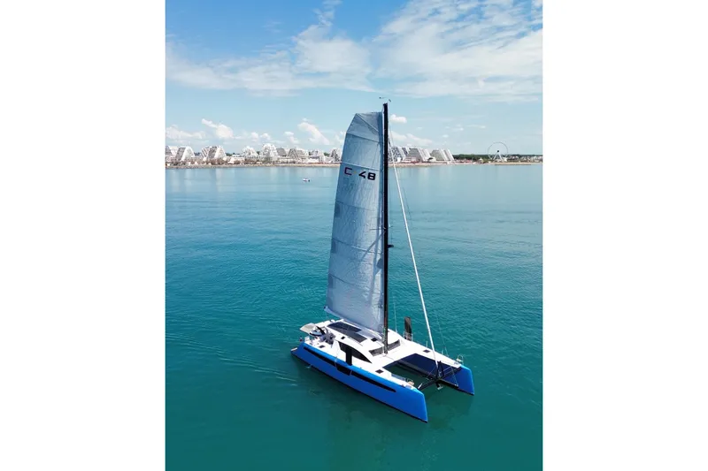 Slide: The Image of 2025 C-Catamarans 48 sailing on calm blue waters near a coastal cityscape. - 6