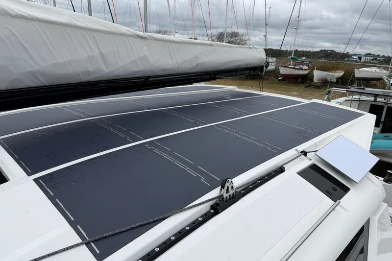 Slide: The Image of 2025 C-Catamarans 48 with solar panels on deck, docked among other boats. - 92