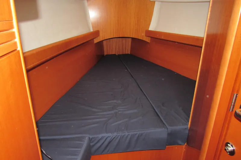Slide: The Image of Interior cabin of 2002 Beneteau First 40.7 sailboat with wooden finish and black bedding. - 6