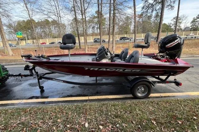 Slide: The Image of 2024 Tracker Pro Team 175 TXW boat on trailer, parked roadside with trees in background. - 8