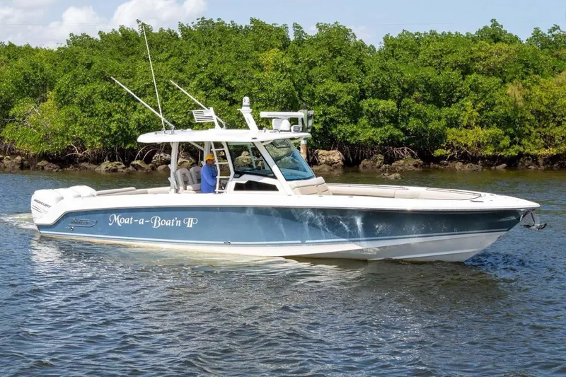 Slide: The Image of 2019 Boston Whaler 380 Outrage boat cruising on a sunny day near lush greenery. - 0