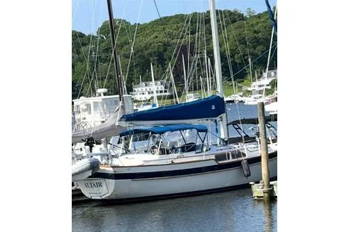 Slide: The Image of 1987 Irwin 43 Mk II Cruiser sailboat docked in a marina with lush greenery. - 3