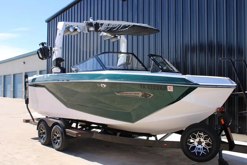 Slide: The Image of 2021 Nautique Super Air Nautique G21 boat on trailer, parked by a building. - 3