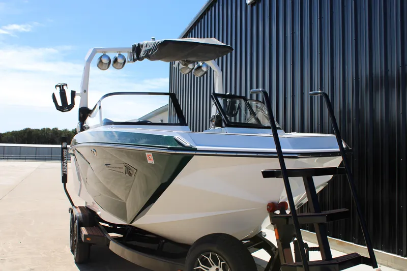 Slide: The Image of 2021 Nautique Super Air Nautique G21 boat on trailer near black building. - 4