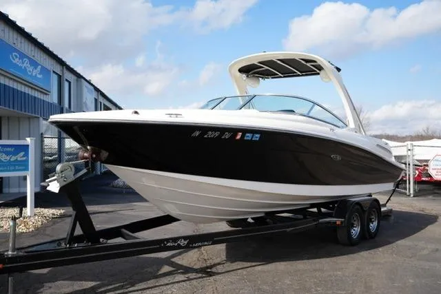 Slide: The Image of 2008 Sea Ray SLX 250 boat on trailer, parked outdoors under a partly cloudy sky. - 2