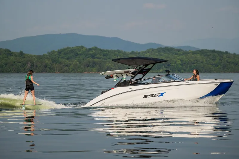Slide: The Image of Manufacturer Provided Image: 2026 Yamaha Boats 255XE on lake with wakeboarder, surrounded by scenic mountains. - 12