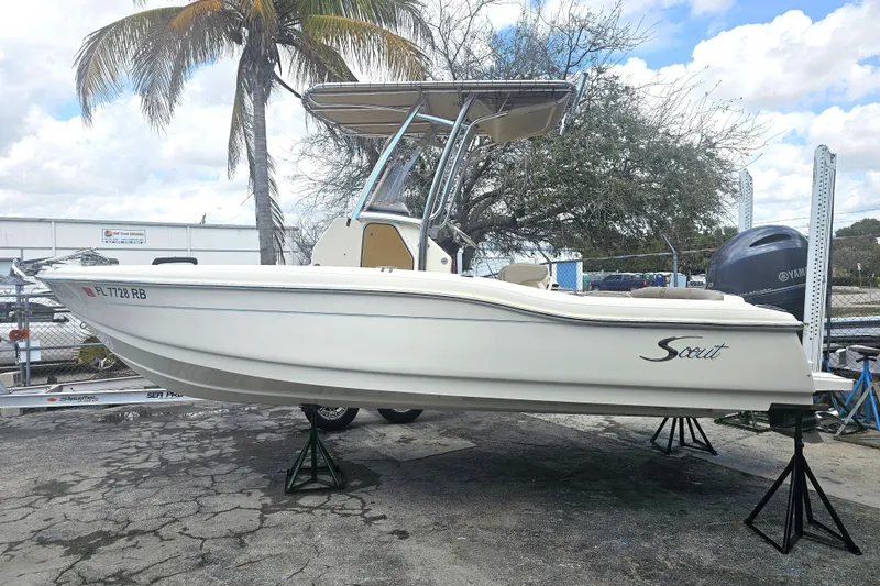 Slide: The Image of 2016 Scout 210 XSF boat on stands, palm tree background, overcast sky. - 22