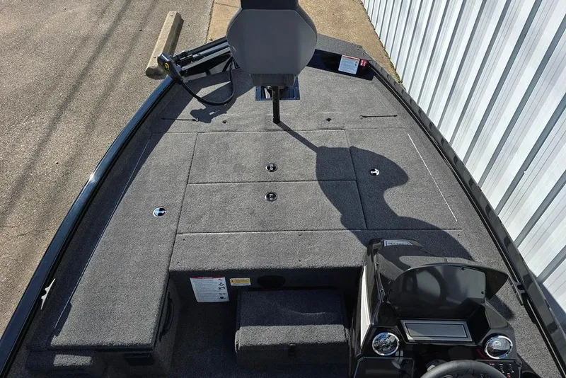 Slide: The Image of 2026 Lowe Stinger 175 boat deck with seating and control panel, parked by a metal fence. - 3