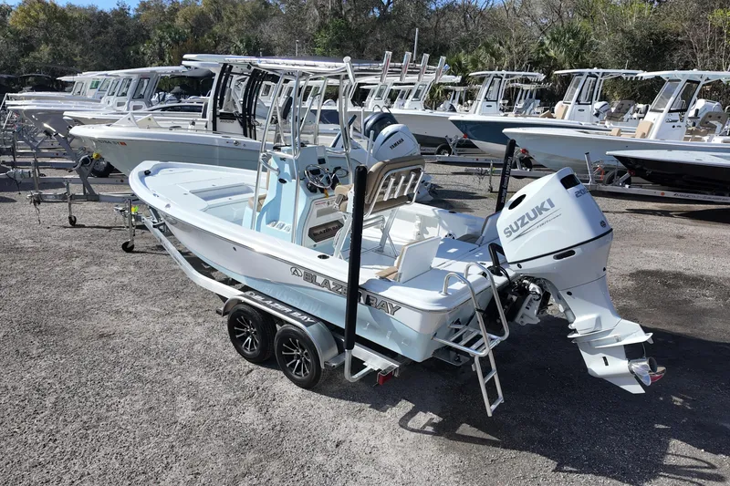 Slide: The Image of 2026 Blazer PureBay 2200 boat with Suzuki engine on trailer in marina. - 2