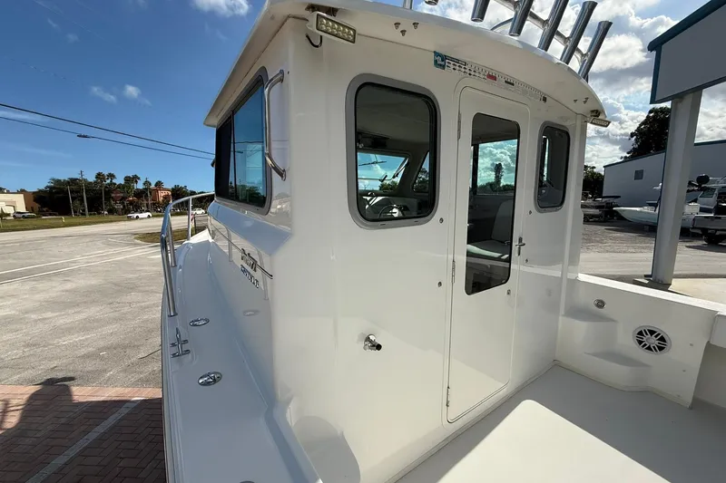 Slide: The Image of 2023 Parker 2520 XLD Sport Cabin boat, white exterior, docked under a clear blue sky. - 16