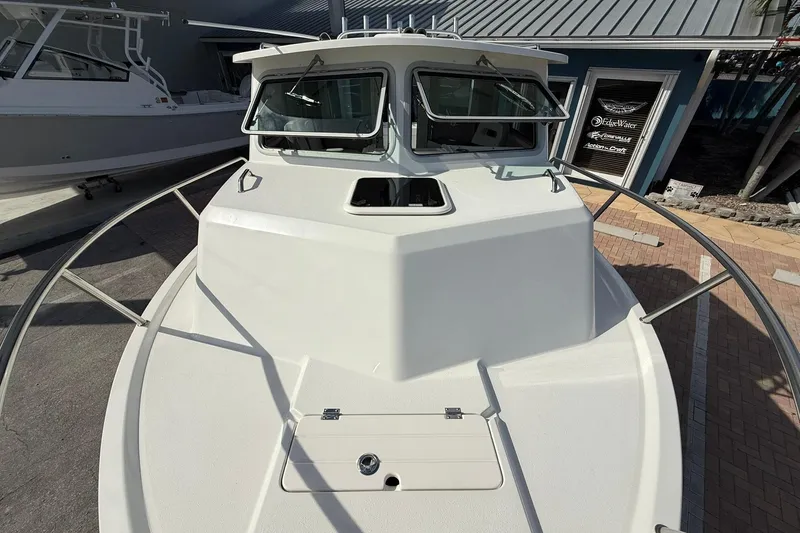 Slide: The Image of 2023 Parker 2520 XLD Sport Cabin boat, front view, docked near a building. - 20