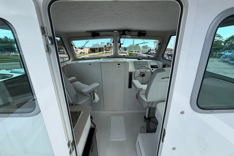 Slide: The Image of Interior of 2023 Parker 2520 XLD Sport Cabin boat, featuring helm and seating. - 23