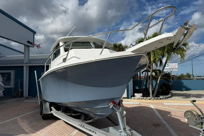 Slide: The Image of 2023 Parker 2520 XLD Sport Cabin boat on trailer, parked outdoors under cloudy sky. - 3