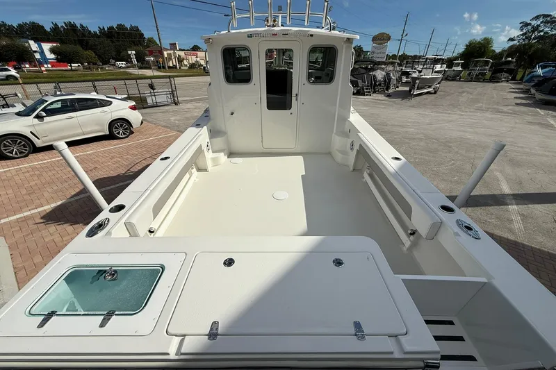 Slide: The Image of 2023 Parker 2520 XLD Sport Cabin boat, spacious deck, parked outdoors. - 9