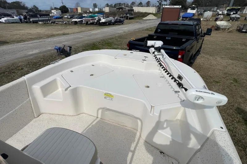 Slide: The Image of 2019 Carolina Skiff 198 DLV boat with Minn Kota trolling motor, parked near a truck. - 21