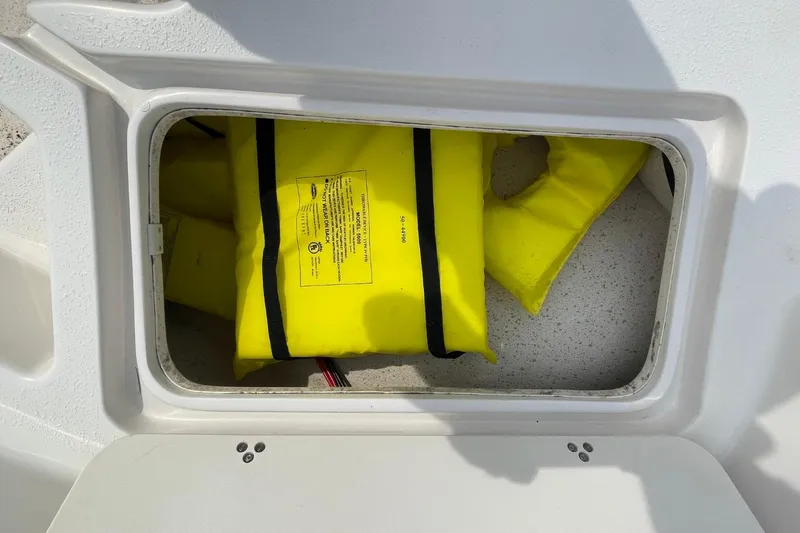 Slide: The Image of Storage compartment with yellow life jackets on a 2019 Carolina Skiff 198 DLV boat. - 25