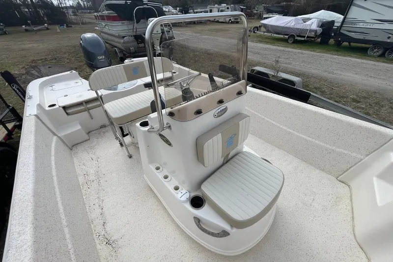 Slide: The Image of 2019 Carolina Skiff 198 DLV boat interior with seating and console, parked outdoors. - 28