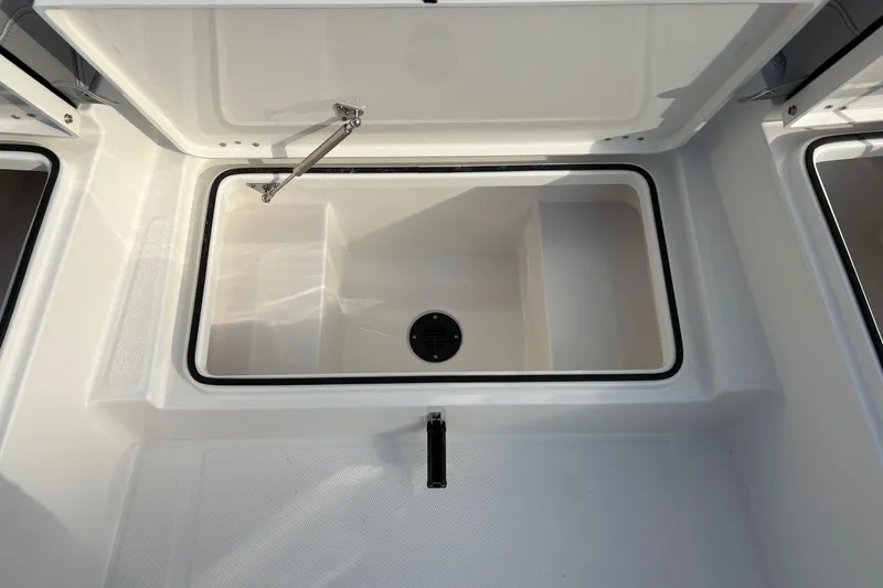 Slide: The Image of 2026 Bay Rider 2460 FS Skiff storage compartment, open lid, white interior. - 17