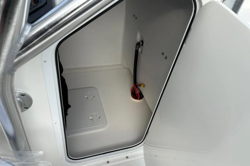 Slide: The Image of 2026 Bay Rider 2460 FS Skiff storage compartment with open door and visible wiring. - 18