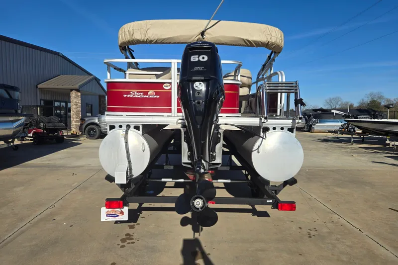 Slide: The Image of 2023 Sun Tracker Bass Buggy 18 DLX pontoon boat with outboard motor, parked outdoors. - 16