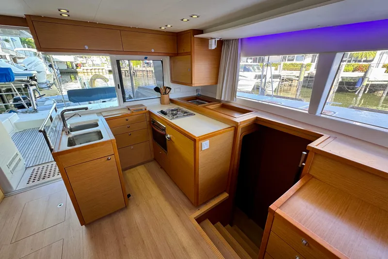 Slide: The Image of Interior of 2012 Lagoon 450 F yacht kitchen with wood cabinetry and marina view. - 12