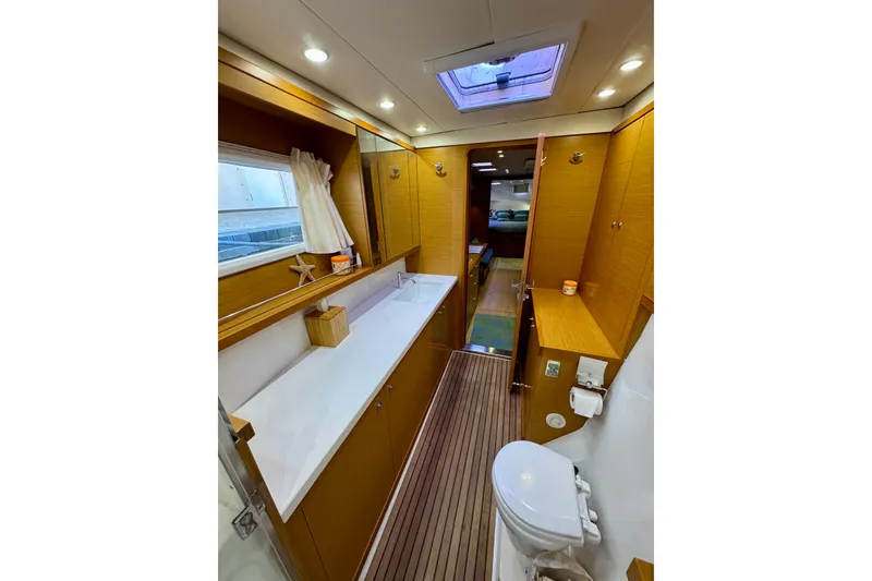 Slide: The Image of Interior of 2012 Lagoon 450 F yacht, featuring a modern bathroom with wood accents. - 21