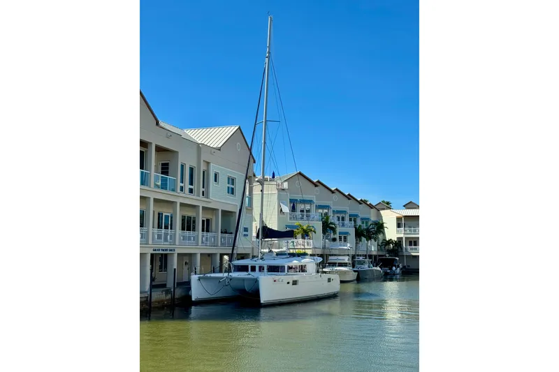Slide: The Image of Lagoon 450 F catamaran docked near waterfront buildings, clear blue sky. - 3
