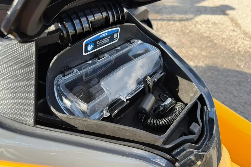 Slide: The Image of 2023 Sea-Doo RXT-X 300 storage compartment with clear cover and coiled cable. - 11