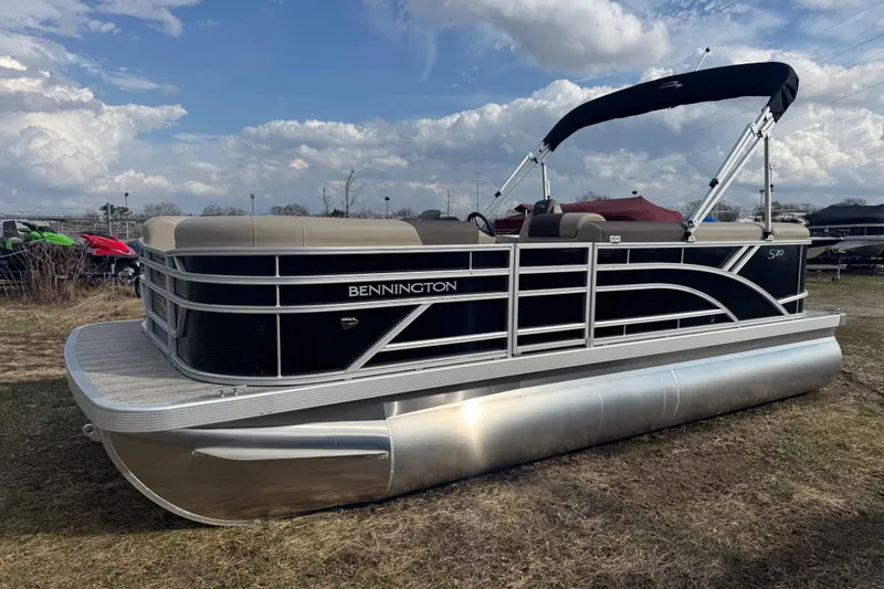 Slide: The Image of 2026 Bennington 20SL pontoon boat with sleek design, parked on grass under cloudy sky. - 2
