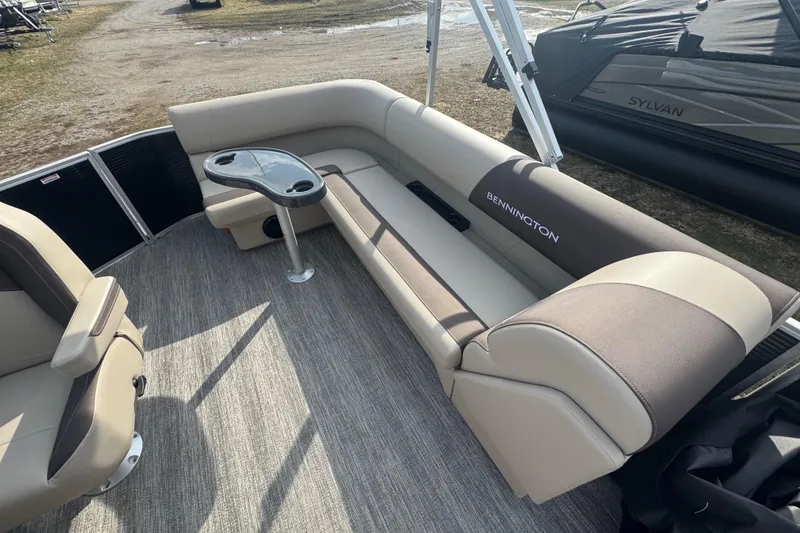 Slide: The Image of 2026 Bennington 20SL pontoon boat interior with beige seating and a small table. - 8