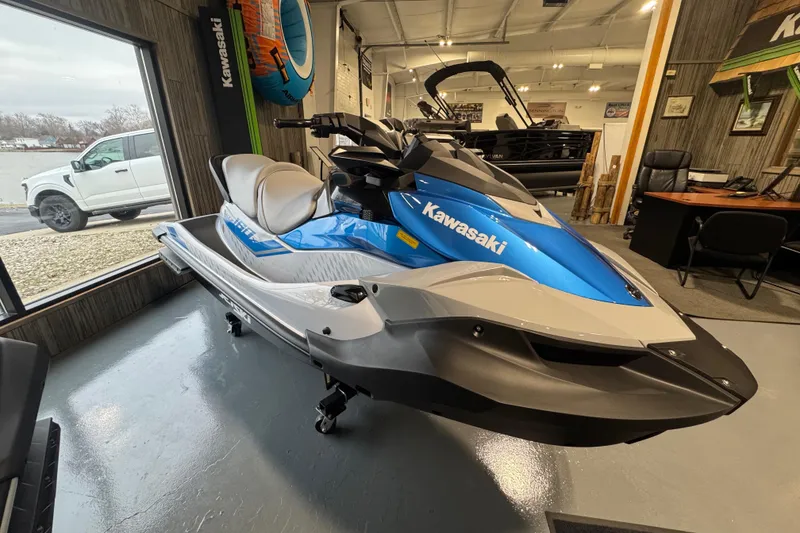 Slide: The Image of 2026 Kawasaki STX160X jet ski in showroom, blue and white design, side view. - 5