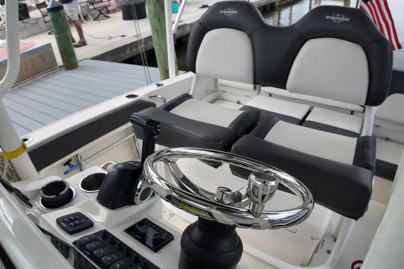 Slide: The Image of 2019 Stingray 236 CC boat interior with steering wheel and seating at dock. - 17