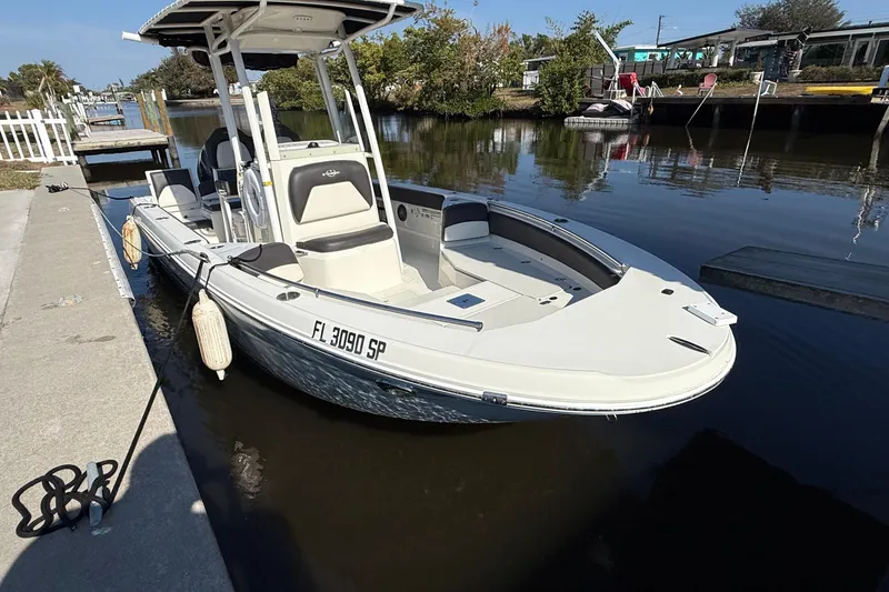 Slide: The Image of 2019 Stingray 236 CC boat on calm water with Yamaha engine and American flag. - 2