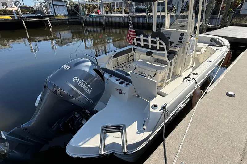 Slide: The Image of 2019 Stingray 236 CC boat docked, featuring Yamaha outboard motor and American flag. - 21