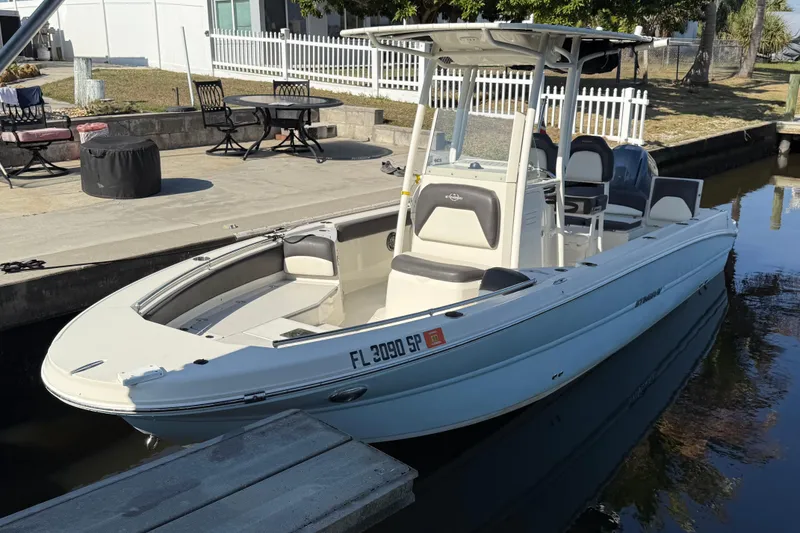 Slide: The Image of 2019 Stingray 236 CC boat docked by a canal with outdoor seating nearby. - 25