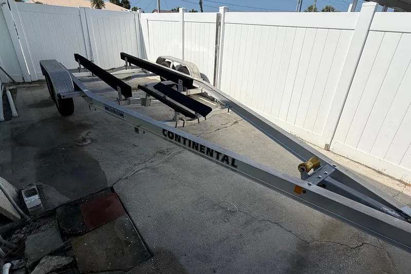 Slide: The Image of Trailer for 2019 Stingray 236 CC boat, parked on concrete near white fence. - 27