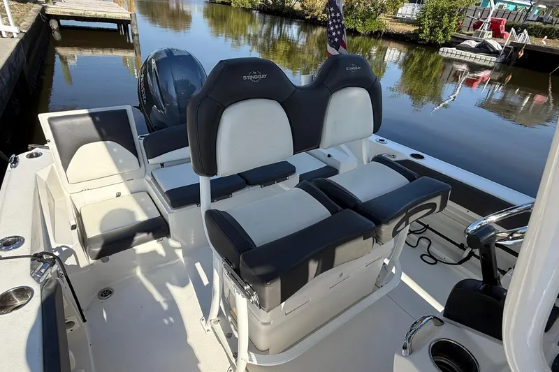 Slide: The Image of 2019 Stingray 236 CC boat on calm water, with a person at the helm. - 5