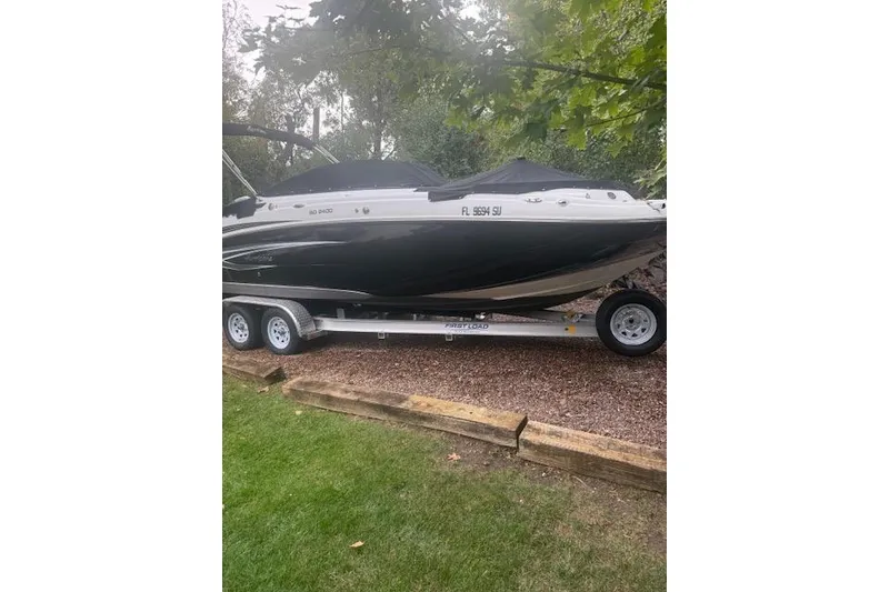 Slide: The Image of 2021 Hurricane SunDeck 2400 OB boat on trailer, parked on grass. - 2