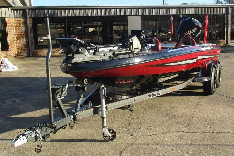 Slide: The Image of 2021 Bass Cat Cougar FTD boat on trailer, red and black, parked outdoors. - 3