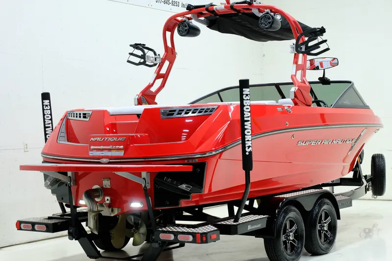 Slide: The Image of Red 2018 Nautique 210 boat on trailer indoors. - 3
