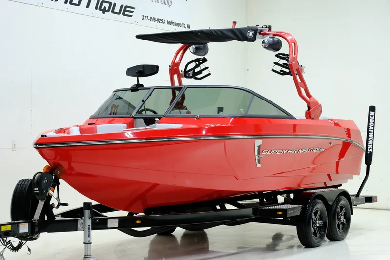 Slide: The Image of Red 2018 Nautique 210 boat on trailer in showroom. - 6
