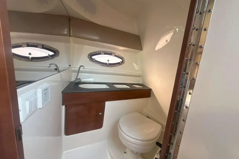 Slide: The Image of 2014 Formula 290 Sun Sport boat bathroom with sink, toilet, and porthole windows. - 45