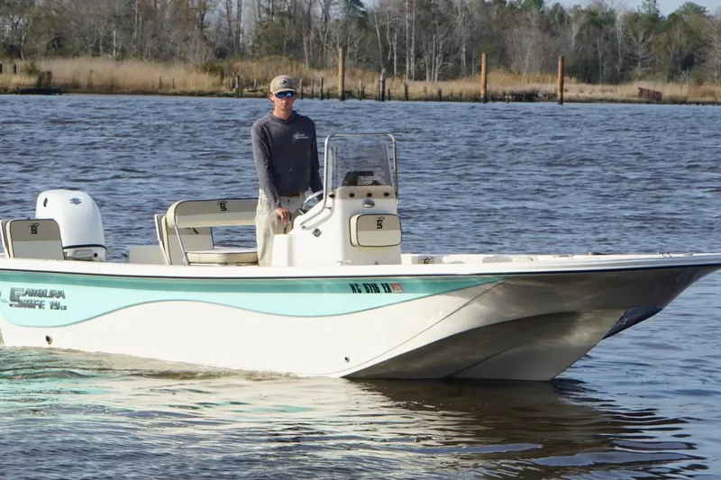 Slide: The Image of 2022 Carolina Skiff 19 LS boat cruising on a calm river with a person steering. - 4