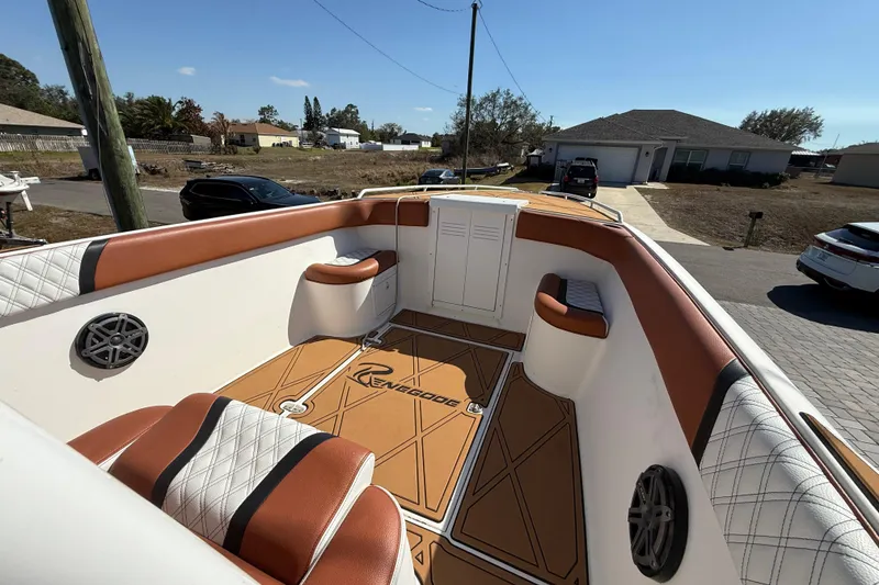 Slide: The Image of 2005 Renegade 29CC boat interior with brown and white seating, parked in a residential area. - 19